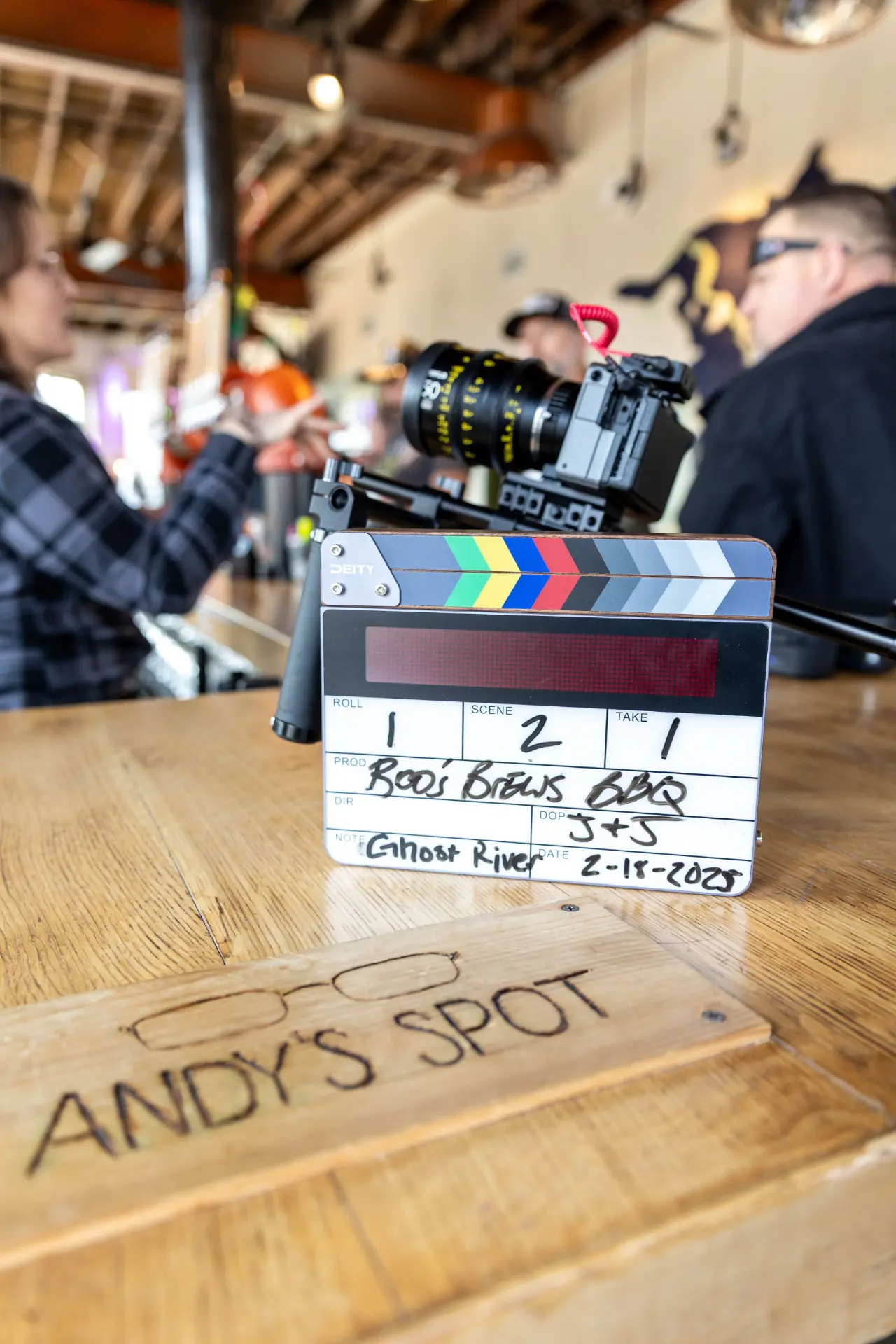A film slate reading Boos Brews BBQ on a bar top during filming